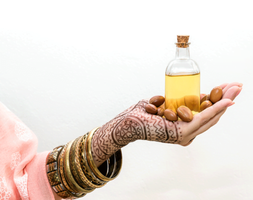 Women in traditional Moroccan attire holding bottles of argan oil, representing the cultural significance and economic empowerment associated with its production.