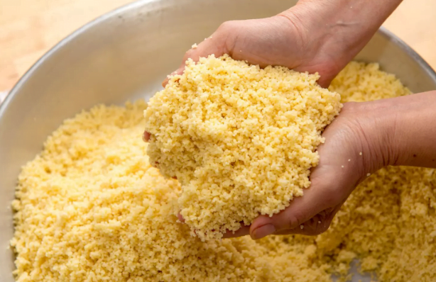 the preparation of Moroccan couscous, including ingredients such as semolina, vegetables, and meat, as well as cooking utensils and traditional Moroccan cooking methods.